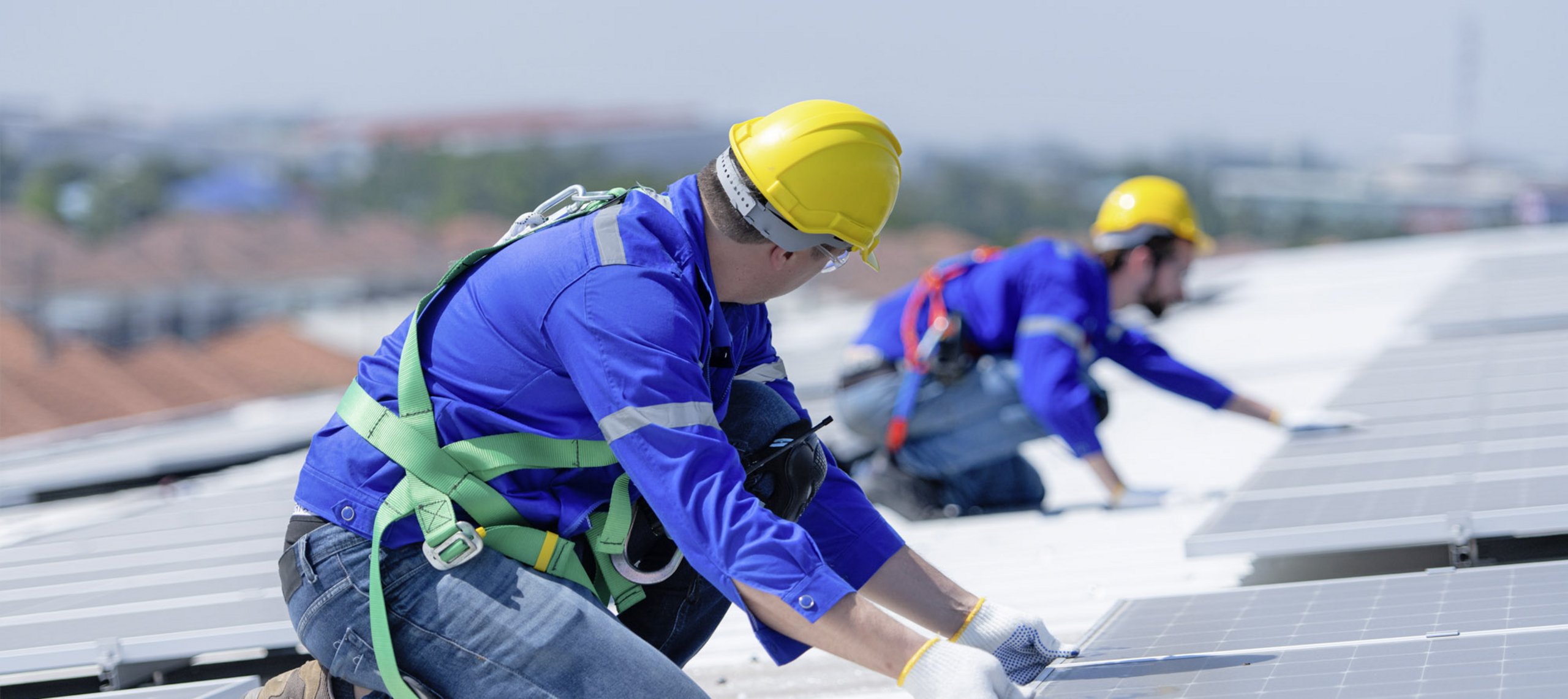 zwei techniker mit gelben helmen beim errichten einer pv-anlage am dach